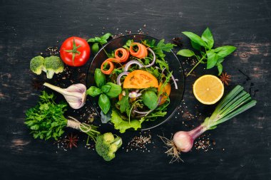 Taze sebze salatası. Roka, domates, havuç, soğan. Ahşap bir arka plan üzerinde. Üstten görünüm. Kopya alanı.