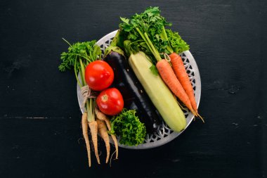 Bir tabak taze sebze. Organik gıda. Ahşap bir arka plan üzerinde. Üstten görünüm. Kopya alanı.