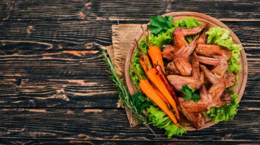Sebze ve havuç ile ızgara tavuk kanatları. Ahşap bir arka plan üzerinde. Üstten görünüm. Kopya alanı.