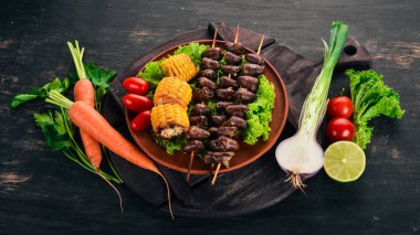 Şiş tavuk kalpler, Mısır ve taze sebze. Ahşap bir arka plan üzerinde. Üstten görünüm. Ücretsiz kopya alanı.