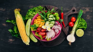 Taze sebze salatası. Mısır, turp, soğan, salatalık, bıldırcın yumurtası. Ahşap bir arka plan üzerinde. Üstten görünüm. Ücretsiz kopya alanı.