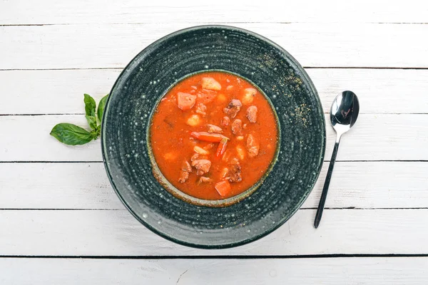 Tomato soup with beef and chili peppers in chervrniy plate. On a wooden table. Top view. Copy space. — Stock Image Tomato Soup Beef Chili Peppers Chervrniy Plate Wooden Table Top Stock Image