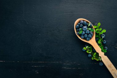 Bir tahta kaşık taze yabanmersini. Ahşap bir masaya. Üstten görünüm. Metniniz için boş alan.