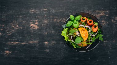 Taze sebze salatası. Roka, domates, havuç, soğan. Ahşap bir arka plan üzerinde. Üstten görünüm. Kopya alanı.