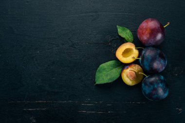 Taze erik yaprakları ile. Meyve. Siyah ahşap arka plan üzerinde. Üstten görünüm. Metniniz için boş alan.