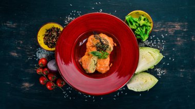 Lahana domates sosu ile kırmızı bir tabak içinde alır. Ahşap bir masaya. Üstten görünüm. Kopya alanı.