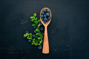 Bir tahta kaşık taze yabanmersini. Ahşap bir masaya. Üstten görünüm. Metniniz için boş alan.