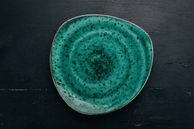 Siyah bir ahşap zemin üzerine mavi tabak. Üstten görünüm. Metniniz için boş alan.