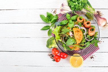 Taze sebze salatası. Roka, domates, havuç, soğan. Ahşap bir arka plan üzerinde. Üstten görünüm. Kopya alanı.