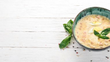 Pastırma, tavuk yumurta, sebze ve fesleğen ile krem çorbası. Ahşap bir masaya. Üstten görünüm. Kopya alanı.