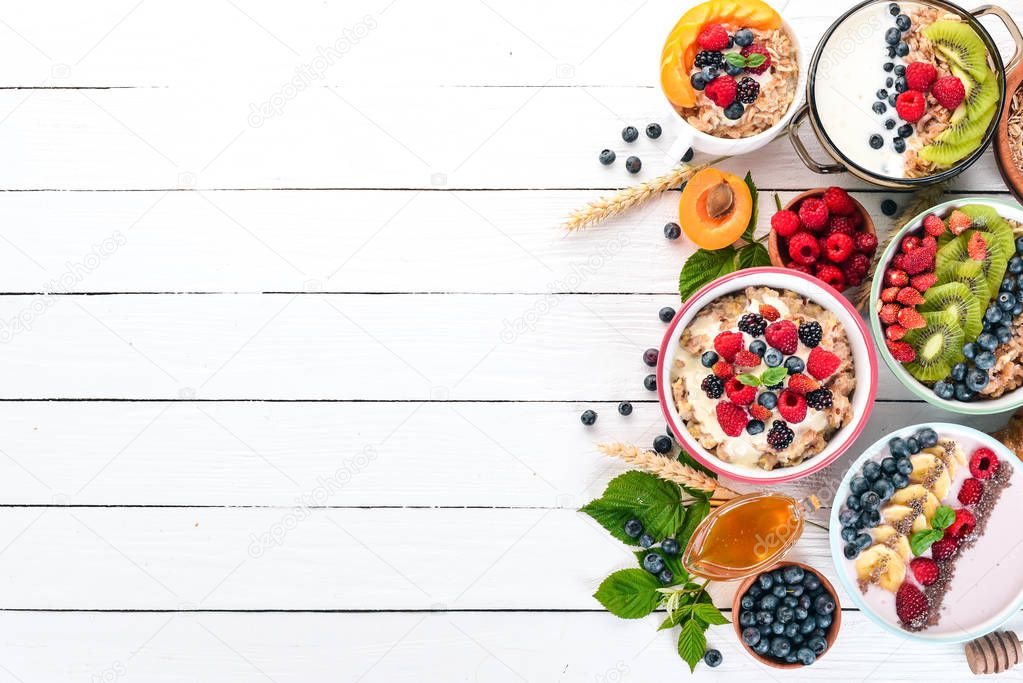 Large Assortment of porridge with fruit and berries. Breakfast. On a white wooden background. Top view. Free space for text.