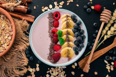 Yoğurt böğürtlen, ahududu ve muz ile. Kalenin içinde. Ahşap bir arka plan üzerinde. Üstten görünüm. Metin için boş alan.