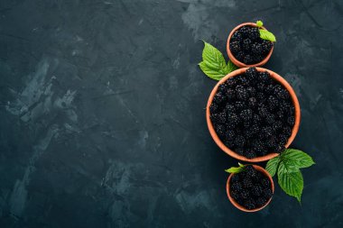 Taze böğürtlen bir tabak içinde. Siyah bir arka plan üzerinde. Üstten görünüm. Metin için boş alan.