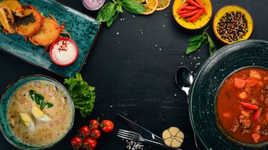 Ahşap bir masa üstünde yiyecek. Domates çorbası, kremalı çorba, patatesli krep lahana ile. Üstten görünüm. Metniniz için boş alan.