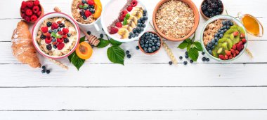 Yulaf lapası meyve ve çilek ile geniş ürün yelpazesine. Kahvaltı. Beyaz ahşap zemin üzerinde. Üstten görünüm. Metin için boş alan.