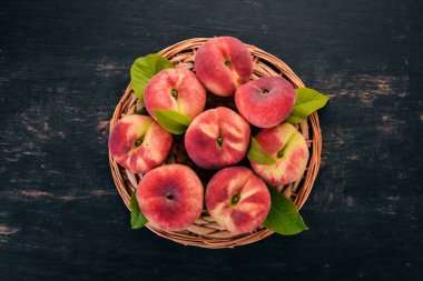 Düz şeftali yeşil siyah bir ahşap arka plan üzerinde bırakır. Üstten görünüm. Metniniz için boş alan.