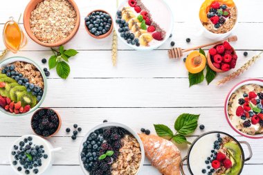 Yulaf lapası meyve ve çilek ile geniş ürün yelpazesine. Kahvaltı. Beyaz ahşap zemin üzerinde. Üstten görünüm. Metin için boş alan.