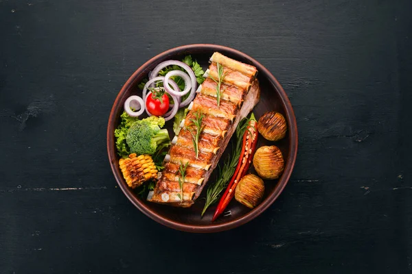 Baked ribs with vegetables. Meat. On a wooden background. Top view. Copy space.