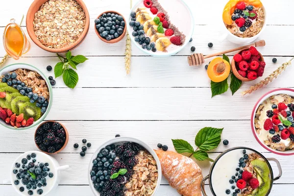 Yulaf lapası meyve ve çilek ile geniş ürün yelpazesine. Kahvaltı. Beyaz ahşap zemin üzerinde. Üstten görünüm. Metin için boş alan.