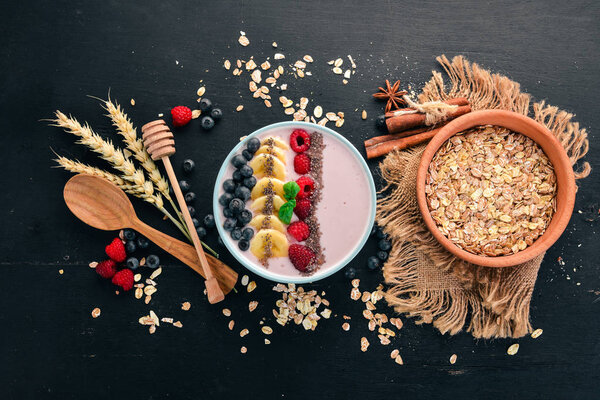 Yogurt with blueberries, raspberries and banana. In the plate. On a wooden background. Top view. Free space for text.
