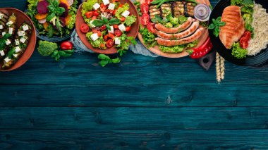 Gıda. Mercimek, yulaf ezmesi, tavuk, domates, sosis, patlıcan. Sağlıklı gıda. Mavi ahşap bir masa üzerinde. Üstten görünüm. Metin için boş alan.