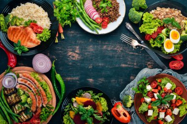 Gıda kümesi. Tavuk göğsü, sosis, patlıcan, domates, taze sebze ızgara. Siyah ahşap bir masa üzerinde. Üstten görünüm. Metin için boş alan.