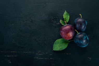 Taze erik yaprakları ile. Meyve. Siyah ahşap arka plan üzerinde. Üstten görünüm. Metniniz için boş alan.