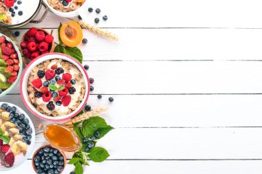 Yulaf lapası meyve ve çilek ile geniş ürün yelpazesine. Kahvaltı. Beyaz ahşap zemin üzerinde. Üstten görünüm. Metin için boş alan.