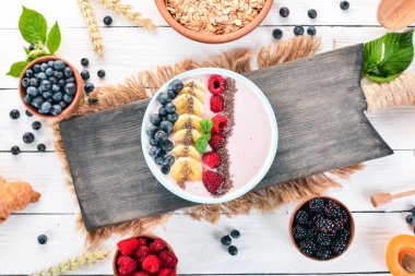 Yoğurt böğürtlen, ahududu ve muz ile. Kalenin içinde. Ahşap bir arka plan üzerinde. Üstten görünüm. Metin için boş alan.