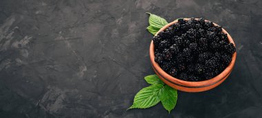 Taze böğürtlen bir tabak içinde. Siyah bir arka plan üzerinde. Üstten görünüm. Metin için boş alan.