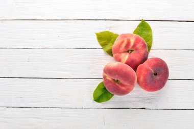 Düz şeftali yeşil beyaz ahşap zemin üzerinde bırakır. Üstten görünüm. Metniniz için boş alan.