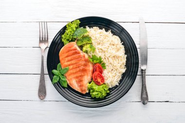 Pirinç ve sebze ızgara tavuk göğsü. Sağlıklı gıda. Beyaz ahşap bir masa üzerinde. Üstten görünüm. Metin için boş alan.