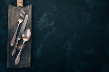 Old cutlery. On a black stone background. Top view. Free space for text. clipart