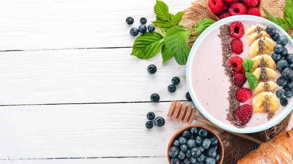 Yoğurt böğürtlen, ahududu ve muz ile. Kalenin içinde. Ahşap bir arka plan üzerinde. Üstten görünüm. Metin için boş alan.