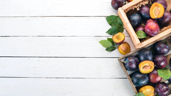 Pruimen Met Bladeren Een Houten Doos Een Witte Houten Achtergrond — Stockfoto