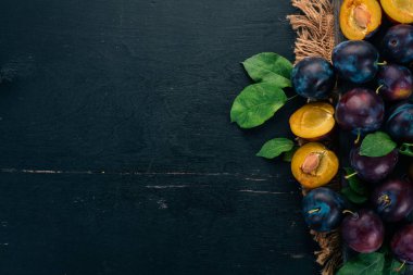 Taze erik yaprakları ile. Meyve. Siyah ahşap arka plan üzerinde. Üstten görünüm. Metniniz için boş alan.