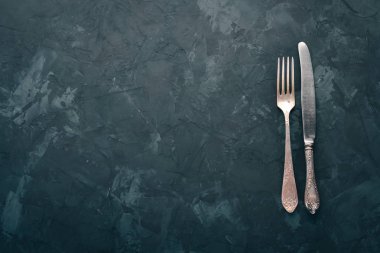 Eski çatal bıçak takımı. Siyah taş arka plan üzerinde. Üstten görünüm. Metin için boş alan.