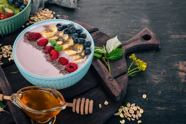 Yoğurt böğürtlen, ahududu ve muz ile. Kalenin içinde. Ahşap bir arka plan üzerinde. Üstten görünüm. Metin için boş alan.