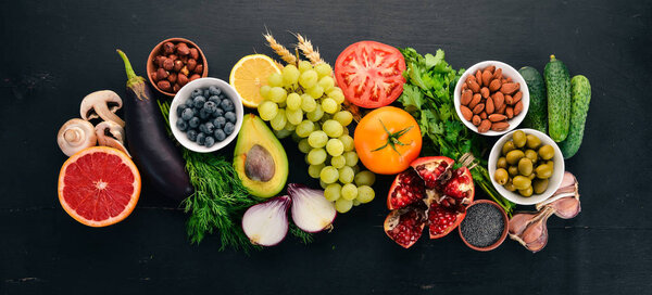 Healthy food clean eating selection: Vegetables, fruits, nuts, berries and mushrooms, parsley, spices. On a black background. Free space for text.
