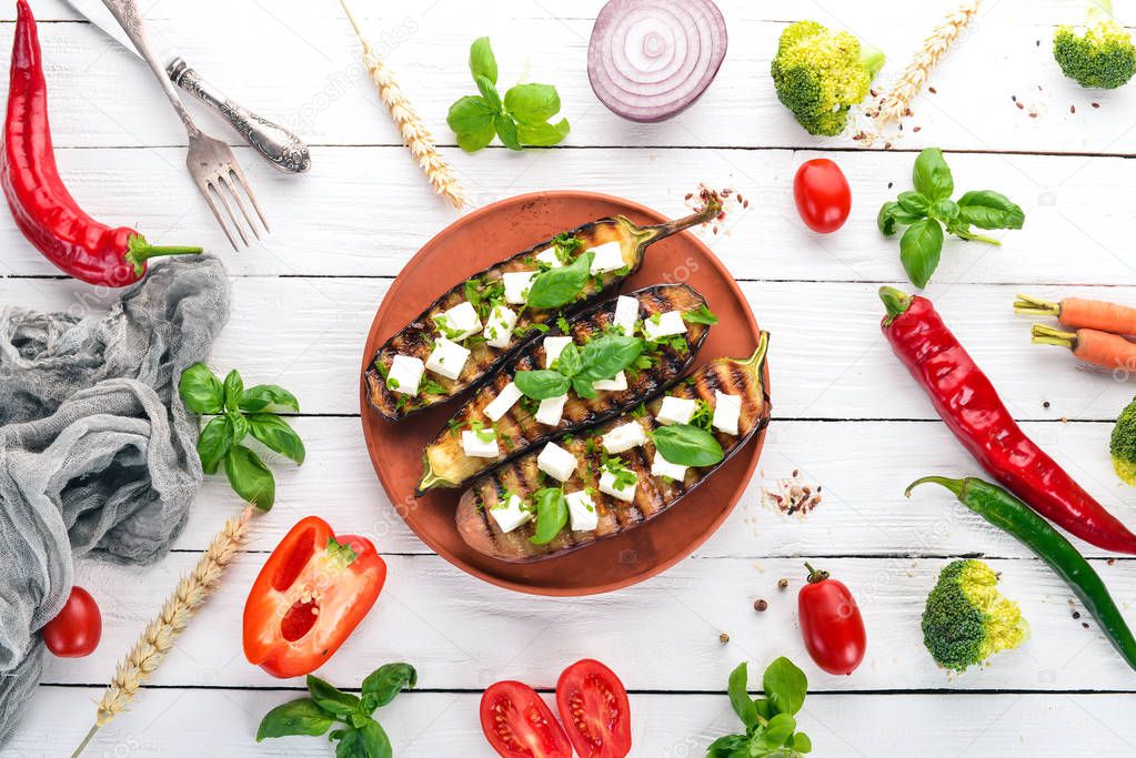 Eggplant grilled with feta cheese and basil. Healthy food. On a white wooden table. Top view. Free space for text.