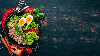 Tavuk yumurta, domates ve sebze yulaf ezmesi. Sağlıklı gıda. Siyah ahşap bir masa üzerinde. Üstten görünüm. Metin için boş alan.