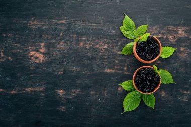 Taze böğürtlen bir tabak içinde. Siyah bir arka plan üzerinde. Üstten görünüm. Metin için boş alan.