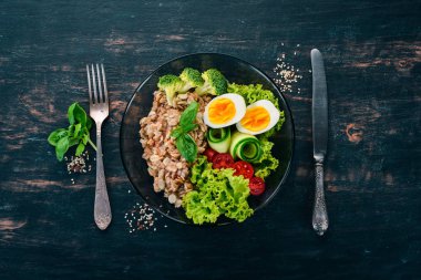 Tavuk yumurta, domates ve sebze yulaf ezmesi. Sağlıklı gıda. Siyah ahşap bir masa üzerinde. Üstten görünüm. Metin için boş alan.