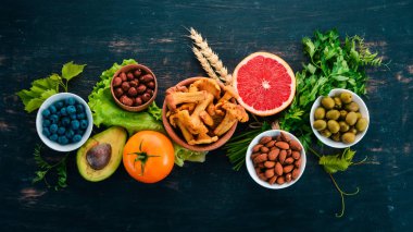 Sağlıklı gıda seçimi yeme temiz: sebze, meyve, fındık, çilek ve mantar, maydanoz, baharatlar. Siyah bir arka plan üzerinde. Metin için boş alan.