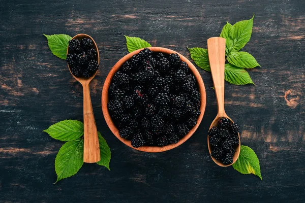 Fresh berries blackberries. On a black wooden background. Top view. Free space for text.
