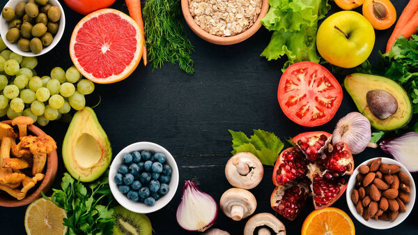 Healthy food clean eating selection: Vegetables, fruits, nuts, berries and mushrooms, parsley, spices. On a black background. Free space for text.