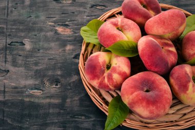 Düz şeftali yeşil siyah bir ahşap arka plan üzerinde bırakır. Üstten görünüm. Metniniz için boş alan.