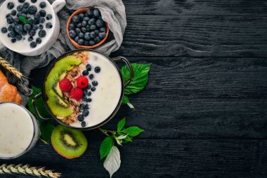Yoğurt ve meyve ve çilek yulaf ezmesi. Kivi, böğürtlen, ahududu. Ahşap bir arka plan üzerinde. Üstten görünüm. Metin için boş alan.