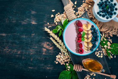 Yoğurt böğürtlen, ahududu ve muz ile. Kalenin içinde. Ahşap bir arka plan üzerinde. Üstten görünüm. Metin için boş alan.