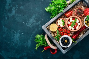 Mozzarella peyniri, domates, fesleğen yaprağı, yağ, zeytin mezarda. Üstten görünüm. Metin için boş alan.